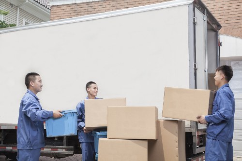 Professional movers carrying boxes from a Kingston flat with stair access